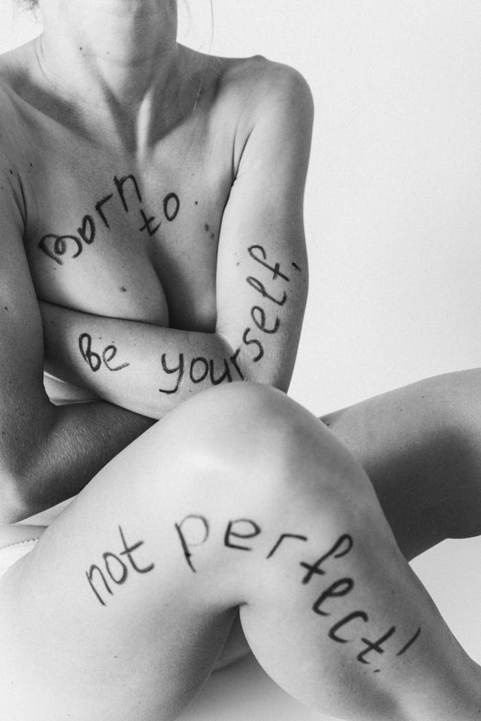 Naked female with be yourself not perfect written on body